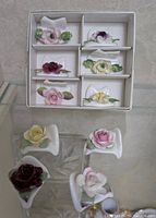 Six floral napkin place settings in original box, each with different colored flowers and green leaves.