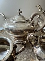 Close-up image showing engraved monogram and ornate spout and handle of the teapot