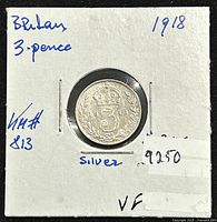 Reverse view of 1917 British 3 pence silver coin showing denomination, crown, date and floral design. Coin held in paper holder with handwritten notes.