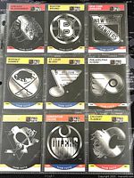 Front view of nine 1990-1 Pro Set hockey team logo trading cards in protective sleeves, each showing team logos in silver foil.