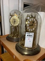 Pair of two vintage windup anniversary clocks with dome covers, shown from front and side angles.