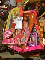 Photo showing three Barbie dolls in their original packaging stacked together, featuring Coca-Cola Party Barbie on top.