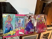 Three Barbie dolls in original packaging displayed side by side, showing their colorful fairytale-themed boxes and detailed costumes.