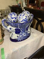 Side view of blue and white porcelain elephant-shaped dish holding three decorative balls.