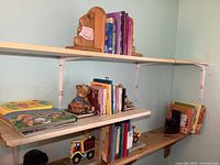 Wide view of wooden shelves holding children's books and a set of brown bear bookends.