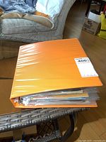 Orange binder filled with vintage comic books on a table.