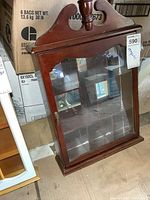 Front view of the wood display cabinet showing glass door and mirrored interior back