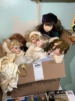 Box with five porcelain dolls showing detailed outfits and faces