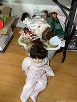 Overview photo showing basket filled with porcelain dolls and one doll seated on floor