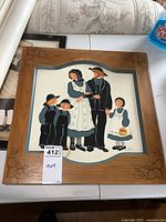 Full view of the framed folk art Amish family painting showing the wooden frame and painting details.