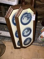 Two octagonal wooden frames each containing three collector plates with blue and white classical or mythological scenes.