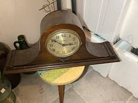 Front view of vintage Ingraham mantle clock with clear clock face and wood finish showing age wear.