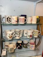 Wide shot of shelf with 12 coffee mugs in various designs and colors