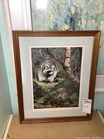 Full view of the framed print featuring the raccoon and natural woodland setting.