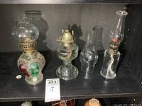 Three smaller vintage glass oil lamps displayed on a shelf, showing overall condition and scale.