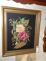 Full view of the framed floral painting with visible signature and gold frame.