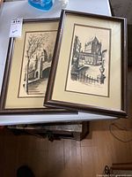 Pair of framed signed black and white architectural prints displayed on a table.