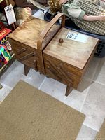 Front view of wooden sewing stand showing closed compartments, handle, and signs of wear.