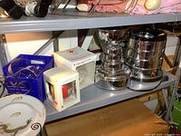 Shelf with NHL Stanley Cup popcorn popper, Christmas ornaments in boxes, blue light box, and hockey sticks visible