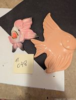 Both fish decorative pieces shown, smaller painted pink and white, larger solid peach