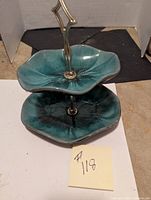 Two tier ceramic serving tray shown from front and top with turquoise glaze and metal handle.