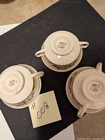 Three cream soup bowls upside down showing the Simpson's Pottery Ambassador Ware marks on bottom.