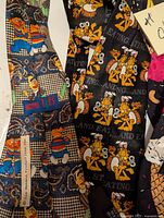 Close-up of two neck ties: one with Sesame Street Muppets pattern, another with Garfield cartoon characters and text