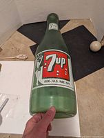 Front view showing 7UP label on the green glass bottle coin bank