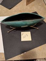 Top view showing the elongated green ceramic bowl with mottled texture resting inside the wire holder