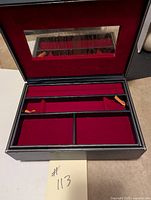 Open blue jewellery box showing interior red velvet compartments and mirror on inner lid