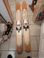 Top view showing the pair of long wooden water skis with white striped design and metal foot bindings.
