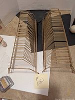 Photo showing two brass record holders side by side on a flat surface with a paper label marked #080.