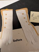 Top view of both white gloves showing front side with four gold buttons and gold trim