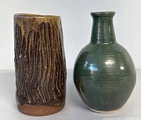 Photo front view of two pottery vases side by side, showing shapes and surface finishes.