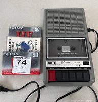 Front view of the Citizen JT1118 cassette recorder with three cassette tapes to the left side.