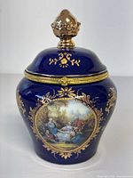 Front view of cobalt blue Limoges trinket box with gold floral accents and painted classical scene
