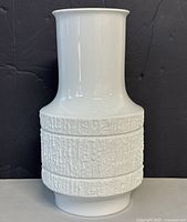 Front view of white bisque porcelain vase showing textured midsection and smooth neck and base.