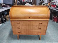 Front view with tambour top closed, showing three lower drawers and integrated handles.