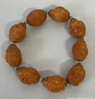 Full view of the circular bracelet showing carved nut beads and turquoise spacer beads.