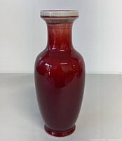 Front view of tall red glazed ceramic vase with smooth finish and gradual color fade.