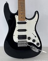 Close-up front of the body showing black gloss finish, pickups, white pickguard, chrome vibrato bridge, and control knobs