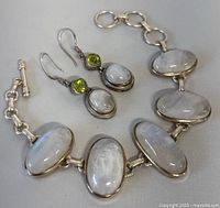Full view of bracelet and earrings together showing moonstone cabochons set in sterling silver and peridot stones in earrings.