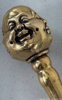 Close-up of one smiling Buddha face made of brass, part of the walking stick handle