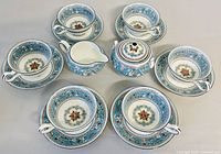 Full view of the set including 5 teacups, 5 saucers, creamer, and sugar bowl arranged on surface showing overall pattern and condition.