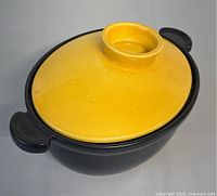 Top and side view of closed vintage porcelain lidded pot showing black base and yellow lid with embossed Appolia name.
