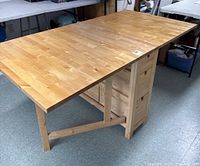 Oblique view of assembled table with both drop leaves extended showing tabletop and central drawer unit