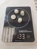 Digital scale displaying four stacks of silver coins and total weight of 133 g