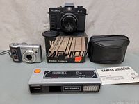 Full lot including Kosako MF-101 35mm camera with box, Kyocera digital camera, Kosako flash, and carrying case