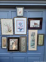 Wide shot showing all 9 framed pictures arranged on a grey door background. Variety of Asian-inspired artwork depicting animals and nature.