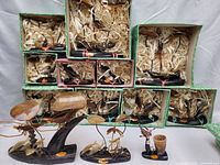 Overview of twelve resin sculptures, mostly shipping boxes with straw packing and three sculptures arranged in front.